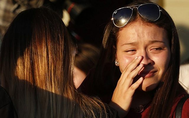 People grieve after placing flowers on a makeshift memorial for the victims of the Marjory Stoneman Douglas High School shooting in Parkland, Florida, on February 15, 2018. (AFP/Rhona Wise)
