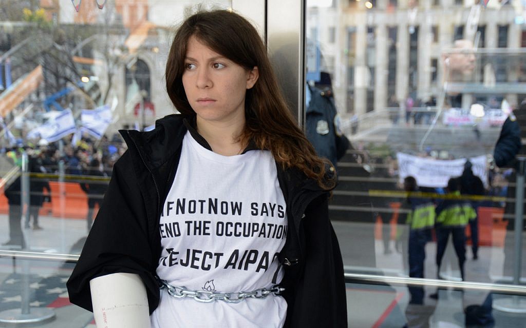 Illustrative: A young Jewish woman in an IfNotNow shirt  is part of a chain of protestors attempting to block the doors at an AIPAC conference in 2017. (Gili Getz)