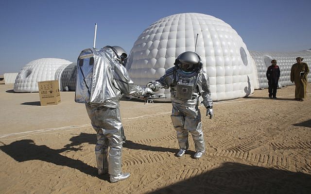 Analog astronaut João Lousada, center, hands his colleague Kartik Kumar a drone while two Omani men watch in front of the Mars simulation base camp in the Dhofar desert of Oman, February 7, 2018. (AP Photo/Sam McNeil)