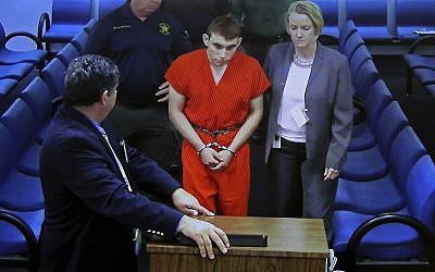 A video monitor shows school shooting suspect Nikolas Cruz (center) with public defender Melisa McNeille (right), making an appearance before Judge Kim Theresa Mollica in the Broward County Court, in Fort Lauderdale, Florida, on Thursday, February 15, 2018. (Susan Stocker/South Florida Sun-Sentinel via AP, Pool)