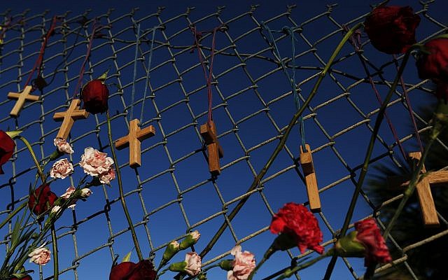 Crosses and flowers hang on a fence near Marjory Stoneman Douglas high school in Parkland, Florida, Saturday, February 16, 2018, in memory of the 17 people killed in a school shooting on Wednesday. (AP Photo/Brynn Anderson)