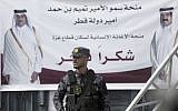 A Palestinian Hamas member stands guard in front of a poster of Qatar's Emir, Sheikh Tamim bin Hamad Al Thani, left, and former Emir of Qatar, Sheikh Hamad bin Khalifa Al Thani, during a press conference with Matthias Schmale, UNRWA's director in Gaza, and the Qatari envoy, Mohammed Al-Emadi, at the Shifa Hospital in Gaza City, Gaza, on February 19, 2018. (AP Photo/ Khalil Hamra)