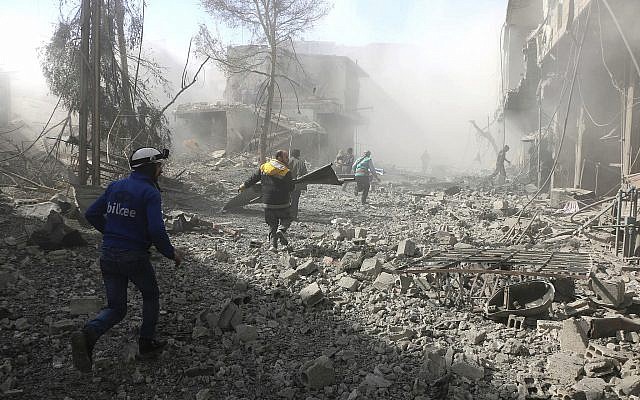 In this photo provided by the Syrian Civil Defense group known as the White Helmets February 20, 2018, shows members of the Syrian Civil Defense running to help survivors from a street that attacked by airstrikes and shelling of the Syrian government forces, in Ghouta. (Syrian Civil Defense White Helmets via AP)