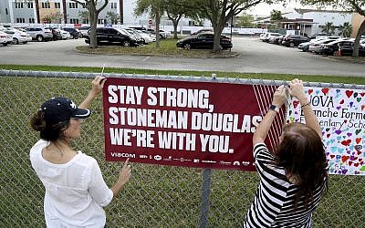 Volunteers hang banners around the perimeter of Marjory Stoneman High School in Parkland, Florida, to welcome back students returning to school Wednesday, February 28, 2018, two weeks after the mass shooting that killed 17 students and staff. (Susan Stocker/South Florida Sun-Sentinel via AP)