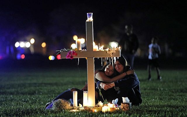 Two people comfort each other as they sit and mourn at one of seventeen crosses, after a candlelight vigil for the victims of the Wednesday shooting at Marjory Stoneman Douglas High School, in Parkland, Florida, February 15, 2018. (AP Photo/Gerald Herbert)