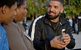 Canadian Jewish rapper Drake (r) gives away a stack of cash to a needy mother and son in his music video 'God's Plan,' released February 16, 2018. (Screen capture: YouTube)