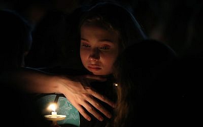 A young girl clutches a friend during candlelight vigil for victims of the mass shooting at Marjory Stoneman Douglas High School yesterday, at Pine Trail Park, in Parkland, Fla., Feb. 15, 2018. (Mark Wilson/Getty Images, via JTA)