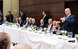 Prime Minister Benjamin Netanyahu, right, addresses dozens of senior business leaders, encouraging them to invest in Israel, ahead of the Munich Security Conference, February 16, 2018. (Amos Ben Gershom/GPO)