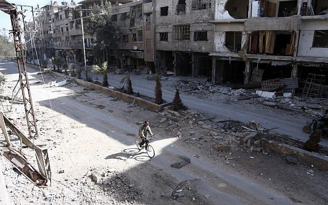A Syrian man rides his bike amidst the destruction in the rebel-held town of Hamouria, in the besieged Eastern Ghouta region on the outskirts of the capital Damascus, on March 9, 2018. (AFP PHOTO / ABDULMONAM EASSA)