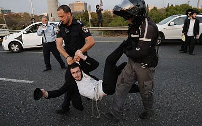 Police remove ultra-Orthodox demonstrators who are blocking a road during a protest against army conscription in the city of Bnei Brak, near Tel Aviv, on March 12, 2018. (AFP PHOTO / Ahmad GHARABLI)