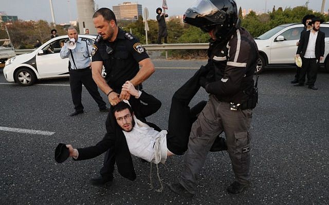 Police remove ultra-Orthodox demonstrators who are blocking a road during a protest against army conscription in the city of Bnei Brak, near Tel Aviv, on March 12, 2018. (AFP PHOTO / Ahmad GHARABLI)