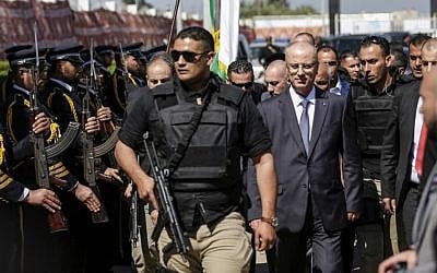Palestinian Authority Prime Minister Rami Hamdallah, second right, escorted by his bodyguards, is greeted by Hamas police forces, left, upon his arrival in Gaza City on March 13, 2018. (AFP Photo/Mahmud Hams)