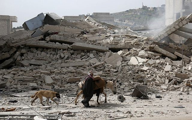 A picture taken on March 22, 2018, shows a man walking with a loaded donkey and followed by a dog past the rubble of a destroyed building in the northwestern Syrian city of Afrin. (AFP PHOTO / Nazeer al-Khatib) A picture taken on March 22, 2018, shows a man walking with a loaded donkey and followed by a dog past the rubble of a destroyed building in the northwestern Syrian city of Afrin. (AFP PHOTO / Nazeer al-Khatib)