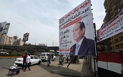 People walk by election campaign posters in support to the Egyptian President for the upcoming presidential election in central Cairo on March 23, 2018.
Egyptians will vote for the presidential election in a March 26-28 poll. ( AFP PHOTO / FETHI BELAID)