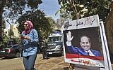 An Egyptian woman walks past an electoral banner commissioned by a member of parliament depicting incumbent President Abdel-Fattah el-Sissi seen with a caption reading in Arabic "for the sake of Egypt we will continue the story of a nation," outside a polling station in the capital Cairo's central neighborhood of Zamalek on March 26, 2018. (AFP PHOTO / KHALED DESOUKI)