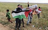 Palestinian children wave a Palestinian flag as they burn a crossed-out poster depicting US President Donald Trump, during a large protest near the southern Gaza city of Khan Younis on March 30, 2018. (Said Khatib/AFP)