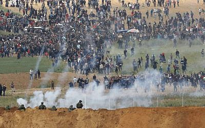A picture taken on March 30, 2018 from the southern Israeli kibbutz of Nahal Oz across the border from the Gaza Strip shows tear gas grenades falling during a Palestinian protest, with Israeli soldiers seen below in the foreground. (AFP PHOTO / Jack GUEZ)