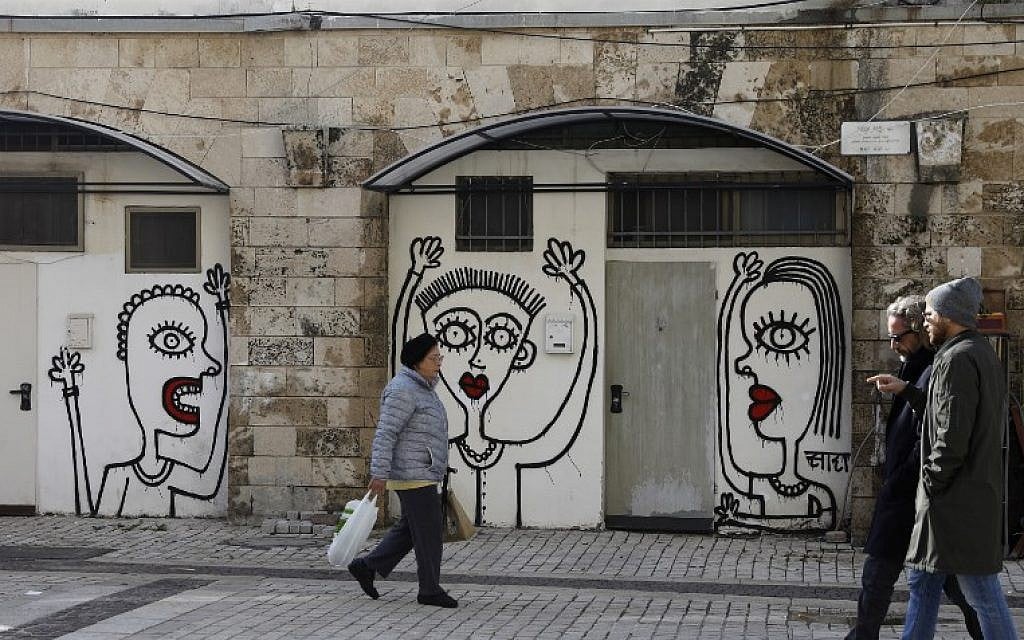 People walk past drawings by New York-based Israeli-born street artist Sara Erenthal in Tel Aviv on January 28, 2018.
(AFP Photo/Menahem Kahana)
