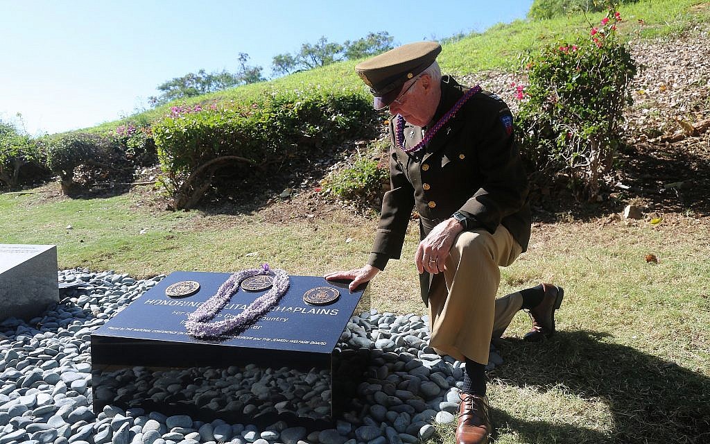 Chaplain Dick Stenbakken kneels by the Chaplains Memorial at the Punchbowl Cemetery. (Courtesy)