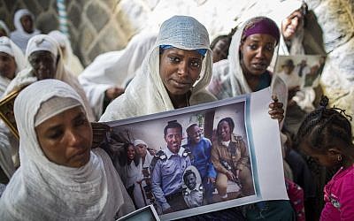 In this Wednesday, February 28, 2018 file photo, Snteayw Girmaw holds a photo of her sister Zemenech Bililin, wearing Israeli military uniform, during a solidarity event at the synagogue in Addis Ababa, Ethiopia. (AP Photo/Mulugeta Ayene, File)
