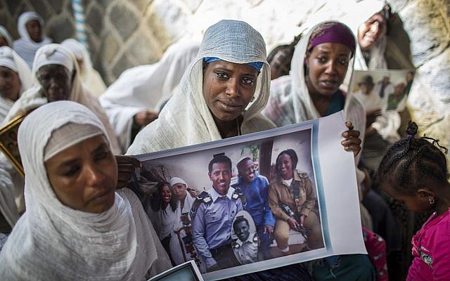 In this Wednesday, February 28, 2018 file photo, Snteayw Girmaw holds a photo of her sister Zemenech Bililin, wearing Israeli military uniform, during a solidarity event at the synagogue in Addis Ababa, Ethiopia. (AP Photo/Mulugeta Ayene, File)