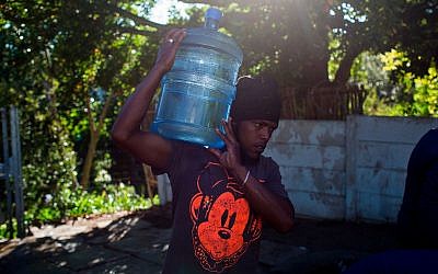 A man carries water at a source for natural spring water in Cape Town, February 1, 2018. (AP Photo/Bram Janssen)