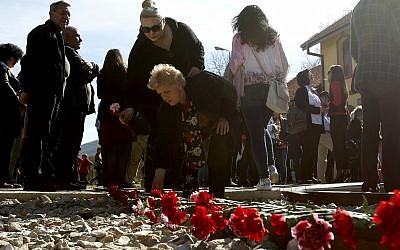 People lay flowers on railway tracks, during a commemoration for the victims of the Holocaust, at the railway station in Bitola, southern Macedonia, on March 11, 2018. (AP Photo/Boris Grdanoski)