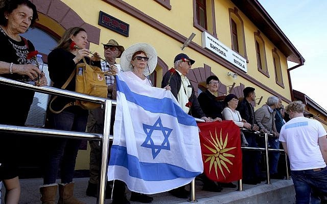 People hold the Israeli and former Macedonian flag as they take part in a commemoration for the victims of the Holocaust, at the railway station in Bitola, southern Macedonia, March 11, 2018. (AP Photo/Boris Grdanoski)