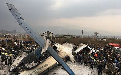 Nepalese rescuers stand near a passenger plane from Bangladesh that crashed at the airport in Kathmandu, Nepal, Monday, March 12, 2018. (AP Photo/Niranjan Shreshta)
