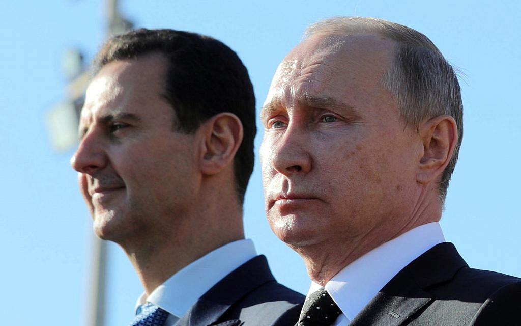 This December 11, 2017 photo shows Russian President Vladimir Putin, right, and Syrian President Bashar Assad watching troops march at the Hemeimeem air base in Syria. (Mikhail Klimentyev, Sputnik, Kremlin Pool Photo via AP)