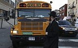 Illustrative: An ultra-Orthodox Jew walks by a Jewish school bus, which has a Yiddish sign on the front, in the Brooklyn neighborhood of Borough Park on January 1, 2014. (Nati Shohat/Flash90)