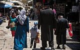 A Palestinian Muslim woman walks by ultra-Orthodox Jewish men in the Muslim Quarter of Jerusalem's Old City, on June 18, 2017. (Hadas Parush/Flash90)