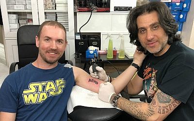 Kyle McKaskle from Louisiana asked Wassim Razzouk to tattoo the word 'Abide' in Greek on his arm. The word is taken from a phrase in the Gospels. (Renee Ghert-Zand/Times of Israel)