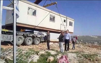 A crane places a caravan on the hilltop of a new industrial zone in the West Bank settlement of Kiryat Arba on March 6, 2018. (Screen capture/Facebook)