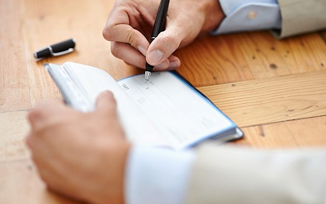 Illustrative: A man writes a check (PeopleImages/Getty Images via JTA) Illustrative: A man writes a check (PeopleImages/Getty Images via JTA)