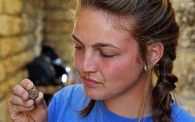 A student from Armstrong College holds a coin discovered at the Ophel archaeological dig outside the walls of Jerusalem's Old City, where a hoard of rare bronze coins from the Jewish Revolt was recently discovered, dating to circa 66-70CE. (Eilat Mazar)