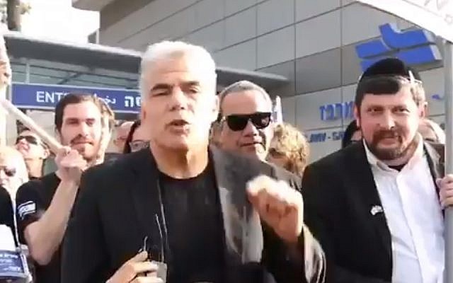 Yesh Atid party leader Yair Lapid (center) protests legislation to exempt ultra-Orthodox yeshiva students from military conscription, next to Dave Mandelshtam, who appeared as an ultra-Orthodox protester but was later revealed to be a Yesh Atid activist who had dressed up, Tel Aviv, March 4, 2018. (Screenshot) Yesh Atid party leader Yair Lapid (center) protests legislation to exempt ultra-Orthodox yeshiva students from military conscription, next to Dave Mandelshtam, who appeared as an ultra-Orthodox protester but was later revealed to be a Yesh Atid activist who had dressed up, Tel Aviv, March 4, 2018. (Screenshot)