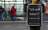 A woman holds a placard as she protests against childbearing abortions in front of the entrance of a local health authority in the Freiham district of Munich, southern Germany, on March 20, 2018. (AFP PHOTO / CHRISTOF STACHE)