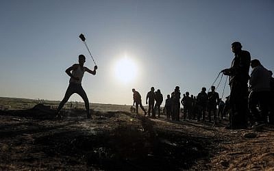 A Palestinian protester hurls stones toward Israeli soldiers during a demonstration along the border with Israel, east of Gaza City on March 31, 2018. (AFP PHOTO / MAHMUD HAMS)