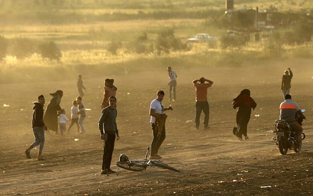 Palestinian protesters run for cover from tear gas fired by Israeli security forces during a protest along the border with Israel, east of Gaza City in the Gaza Strip on March 31, 2018. (AFP PHOTO / MAHMUD HAMS) Palestinian protesters run for cover from tear gas fired by Israeli security forces during a protest along the border with Israel, east of Gaza City in the Gaza Strip on March 31, 2018. (AFP PHOTO / MAHMUD HAMS)