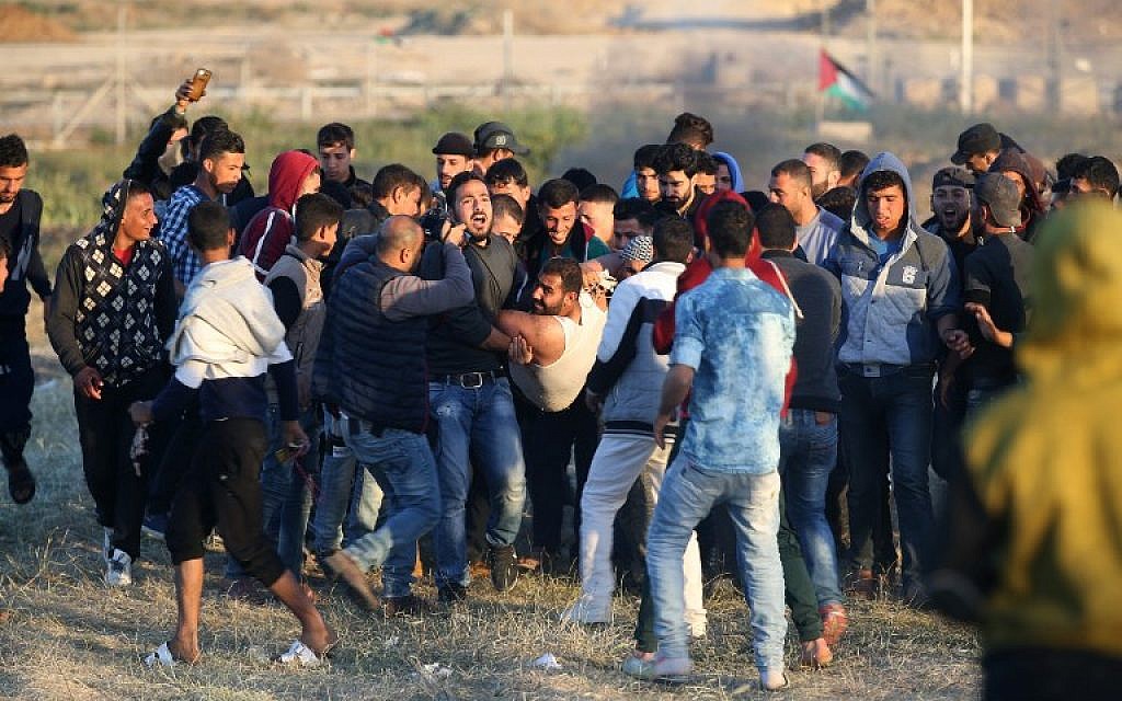 Palestinian protesters carry an injured comrade during clashes with Israeli forces following a protest along the border with Israel, east of Gaza City on April 1, 2018.(AFP PHOTO / Mohammed ABED)
