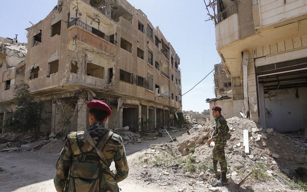 Regime forces walk along a destroyed street in the former rebel-held town of Jobar in Eastern Ghouta on April 2, 2018. (AFP PHOTO / Louai Beshara)