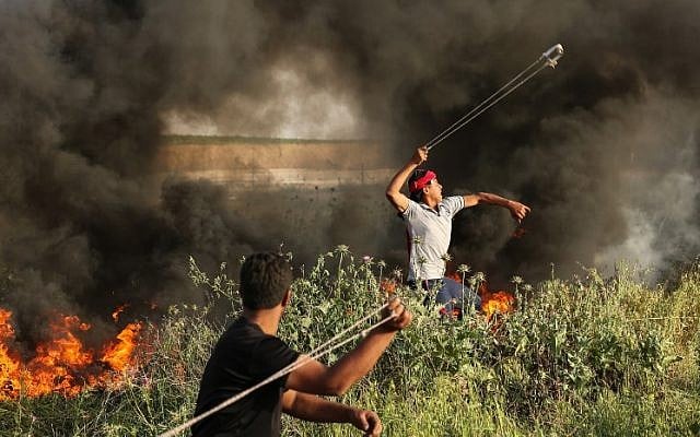 Palestinian protesters use slingshots to throw stones during clashes with Israeli forces at the Israel-Gaza border east of Gaza City on April 4, 2018. (AFP PHOTO / MAHMUD HAMS) Palestinian protesters use slingshots to throw stones during clashes with Israeli forces at the Israel-Gaza border east of Gaza City on April 4, 2018. (AFP PHOTO / MAHMUD HAMS)
