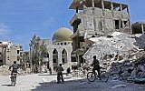 Syrian children ride their bike past destroyed buildings in the former rebel-held town of Zamalka, in Eastern Ghouta on April 5, 2018. (AFP PHOTO / STRINGER)
