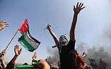 Palestinian demonstrators wave their national flag and shouts slogans against Israeli security forces during a protest on the Israel-Gaza border in the northern Gaza Strip on April 6, 2018. (AFP/Mohammed Abed)