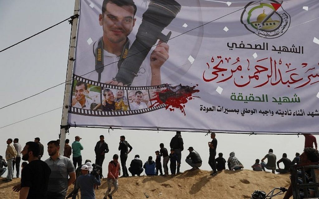Palestinians gather near a banner in memory of Yasser Murtaja, a Gaza reporter killed last week by Israeli fire, during a protest at the border fence with Israel, east of Khan Yunis in the southern Gaza city, on April 13, 2018. (AFP PHOTO / Thomas COEX)