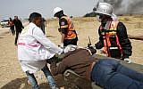 Illustrative: Palestinians paramedics evacuating an injured protester near the border fence with Israel, east of Khan Yunis, in the southern Gaza city, on April 13, 2018. (AFP PHOTO / Thomas COEX)