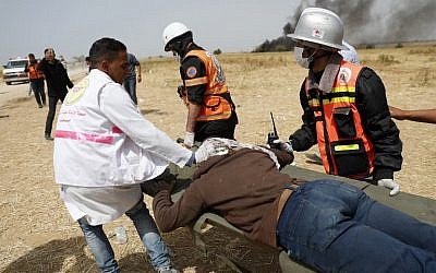 Illustrative: Palestinians paramedics evacuating an injured protester near the border fence with Israel, east of Khan Yunis, in the southern Gaza city, on April 13, 2018. (AFP PHOTO / Thomas COEX)