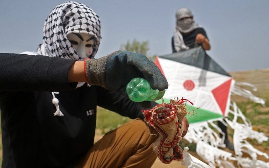 Palestinians on the eastern outskirts of Gaza City prepare a firebomb to attach to a kite and fly over the border fence with Israel, on April 20, 2018. (AFP Photo/Mohammed Abed)