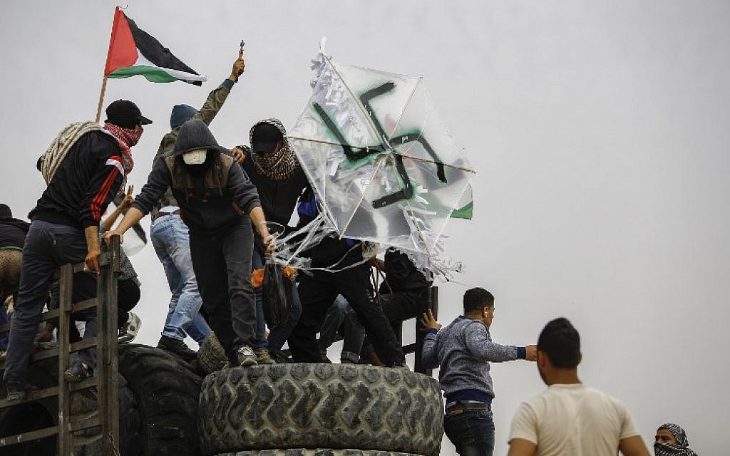 Palestinians hold a kite adorned with a swastika that is carrying a bombnear the border with Israel east of Gaza City, on April 20, 2018. (AFP Photo/Mohammed Abed)